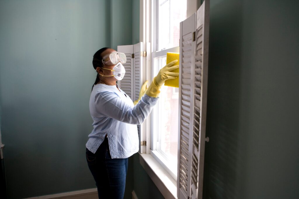 Mulher realiza higienização de janela.